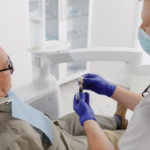 Dentist showing male patient a dental implant during a