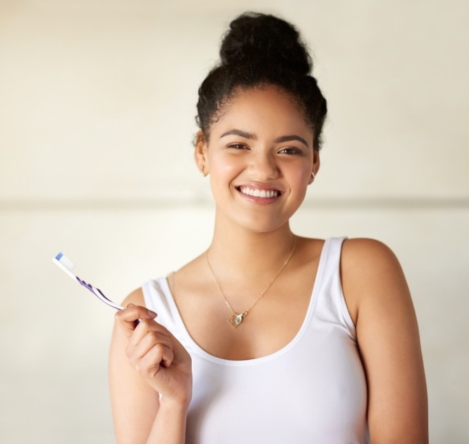 Woman in white shirt holding a toothbrush